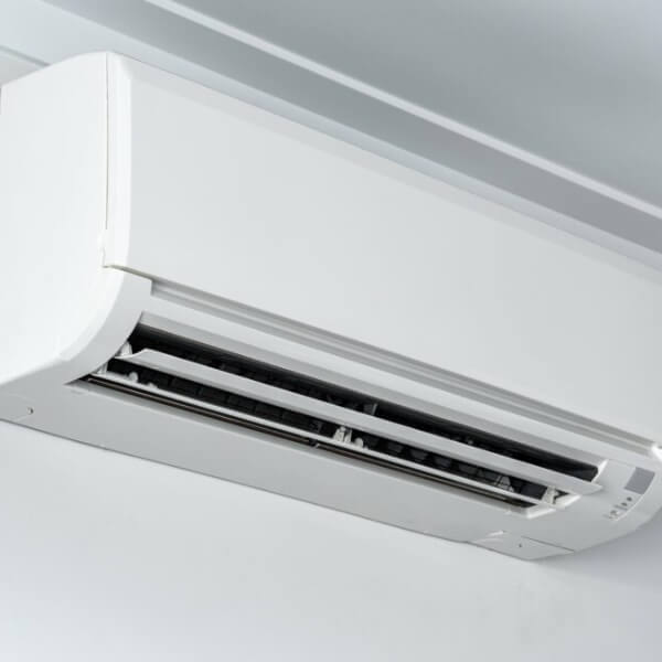 An Air-Conditioning unit mounted on the wall near the ceiling of the room; with the vents open.
