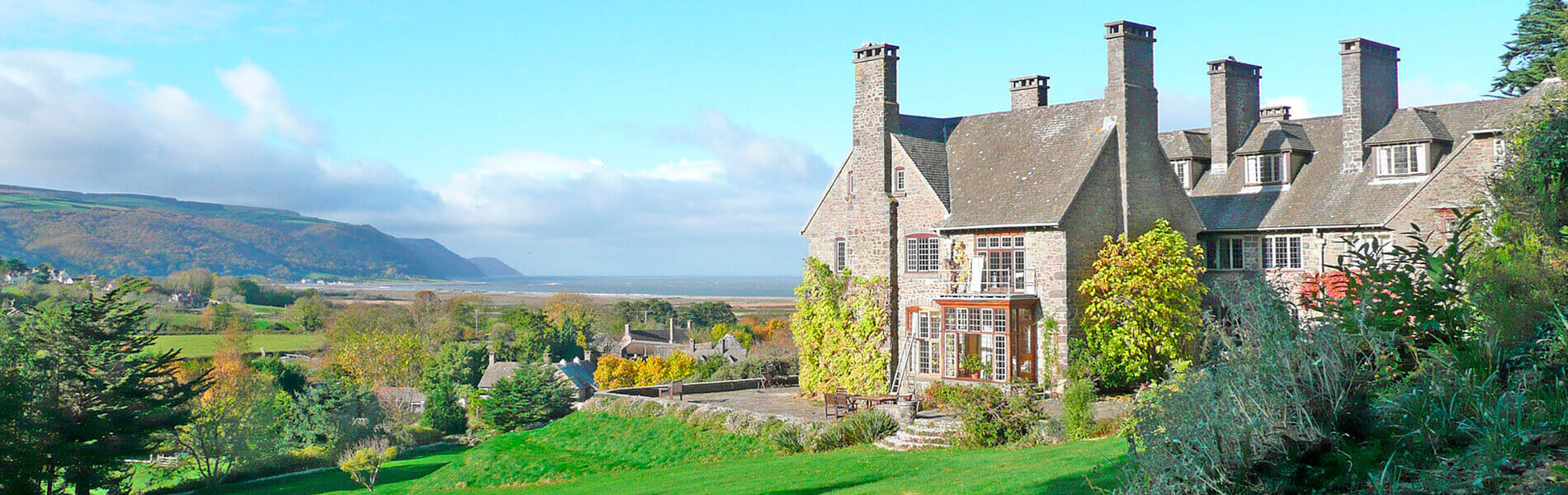View of Bossington Hall Hotel, including the front lawn and surrounding countryside.